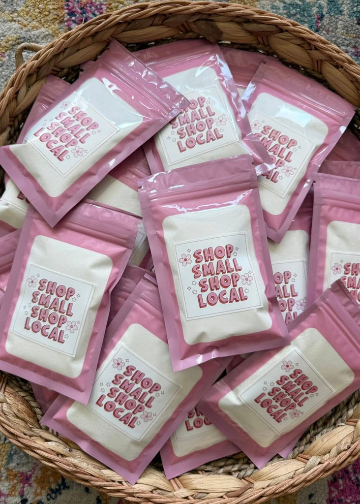 Basket filled with pink packages featuring 'Shop Small Shop Local' text.