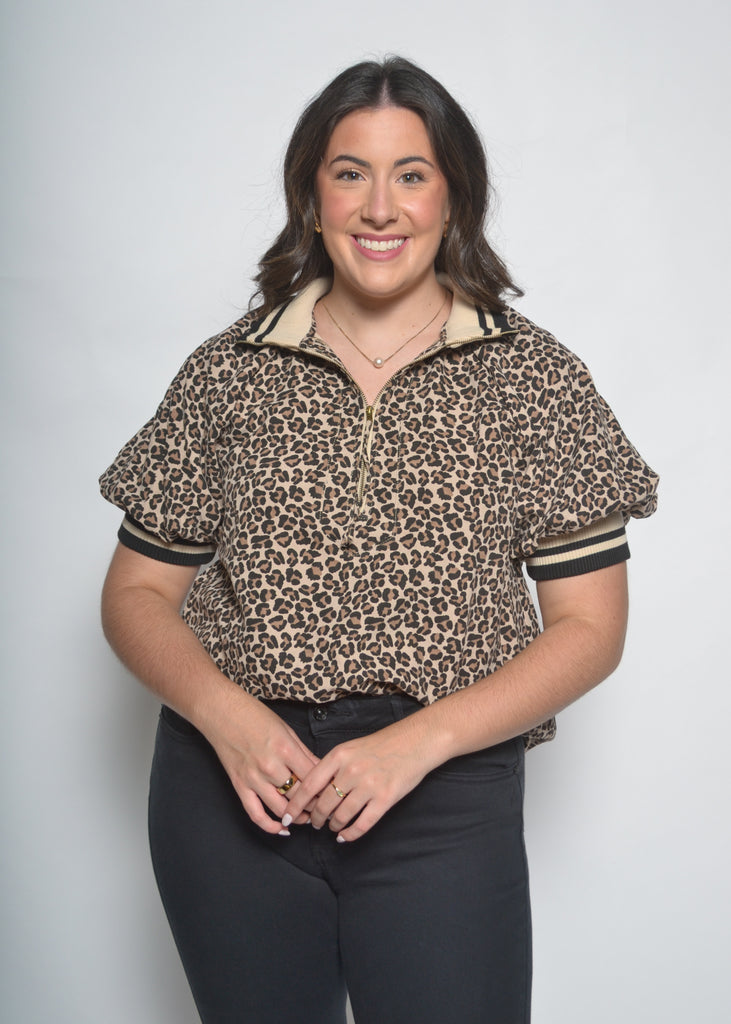 Woman wearing a leopard print blouse with black pants on a white background