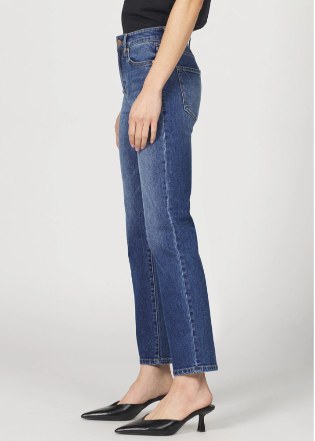 Person wearing blue jeans and black shoes on a white background