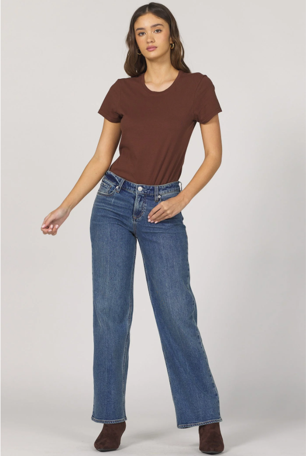 Woman wearing a brown t-shirt and blue jeans on a white background