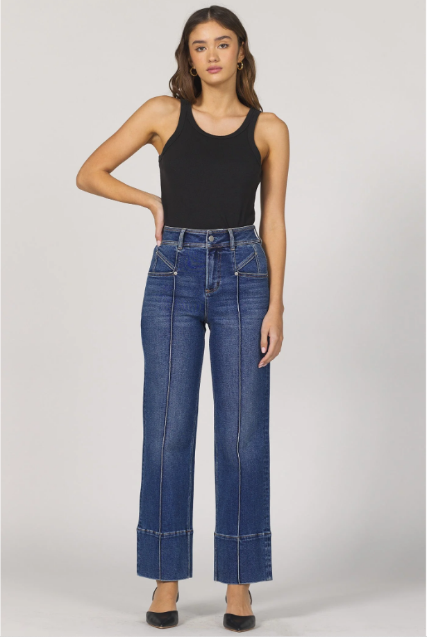 Woman wearing a black tank top and blue jeans on a white background