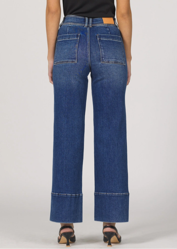 Person wearing blue jeans on a plain background