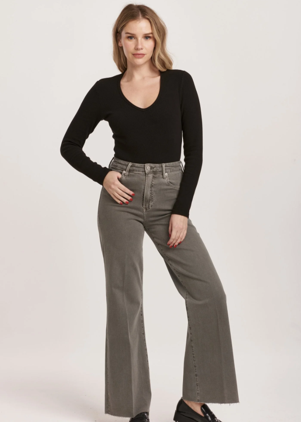Woman wearing a black top and gray flared jeans on a white background