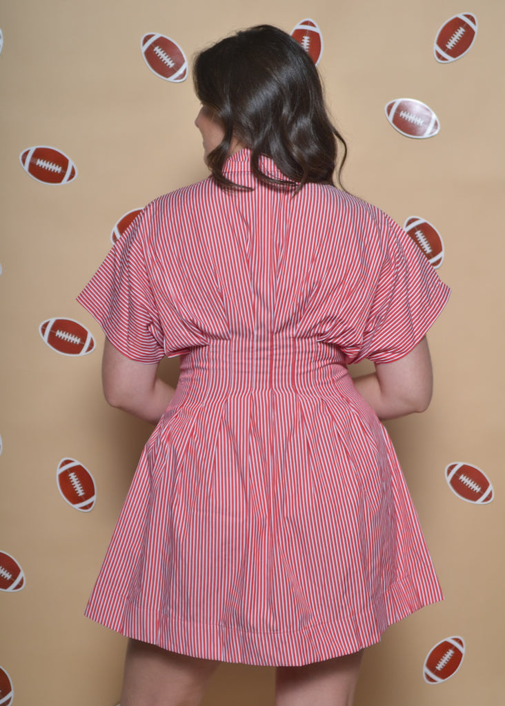 Person wearing a red striped dress with football graphics on a beige background