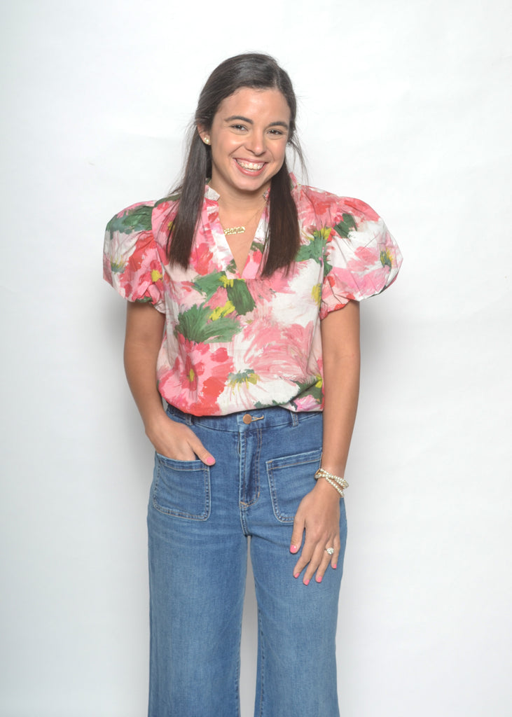 Woman wearing a floral blouse and blue jeans against a white background