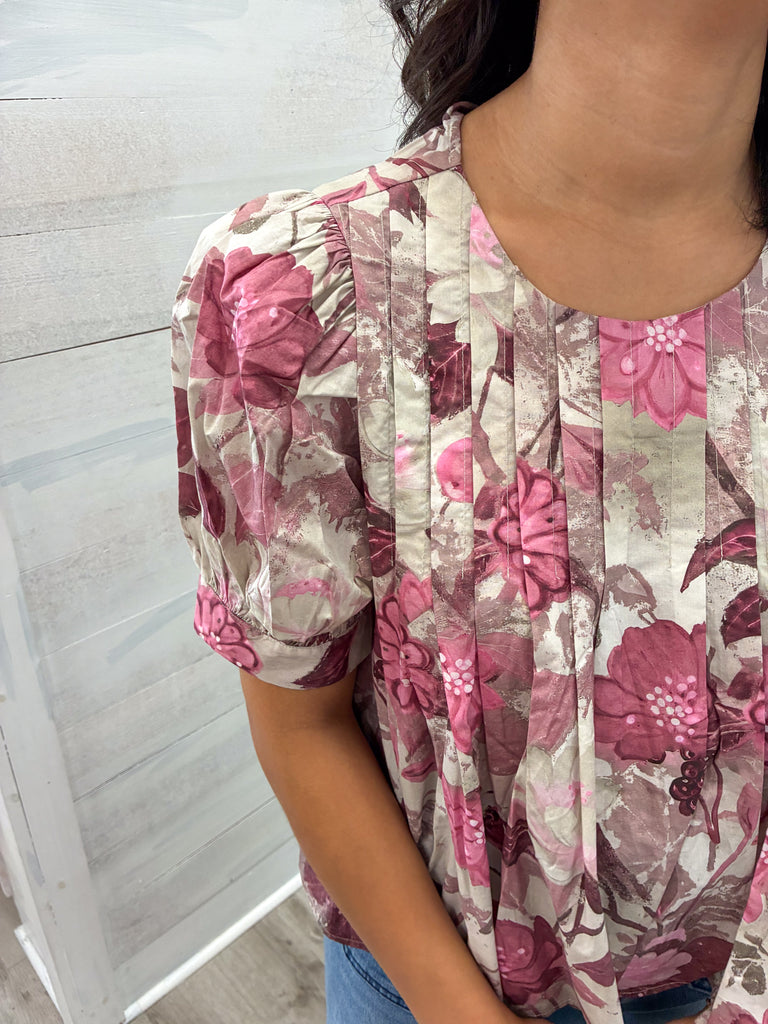 Person wearing a floral dress with pink and purple flowers on a light background