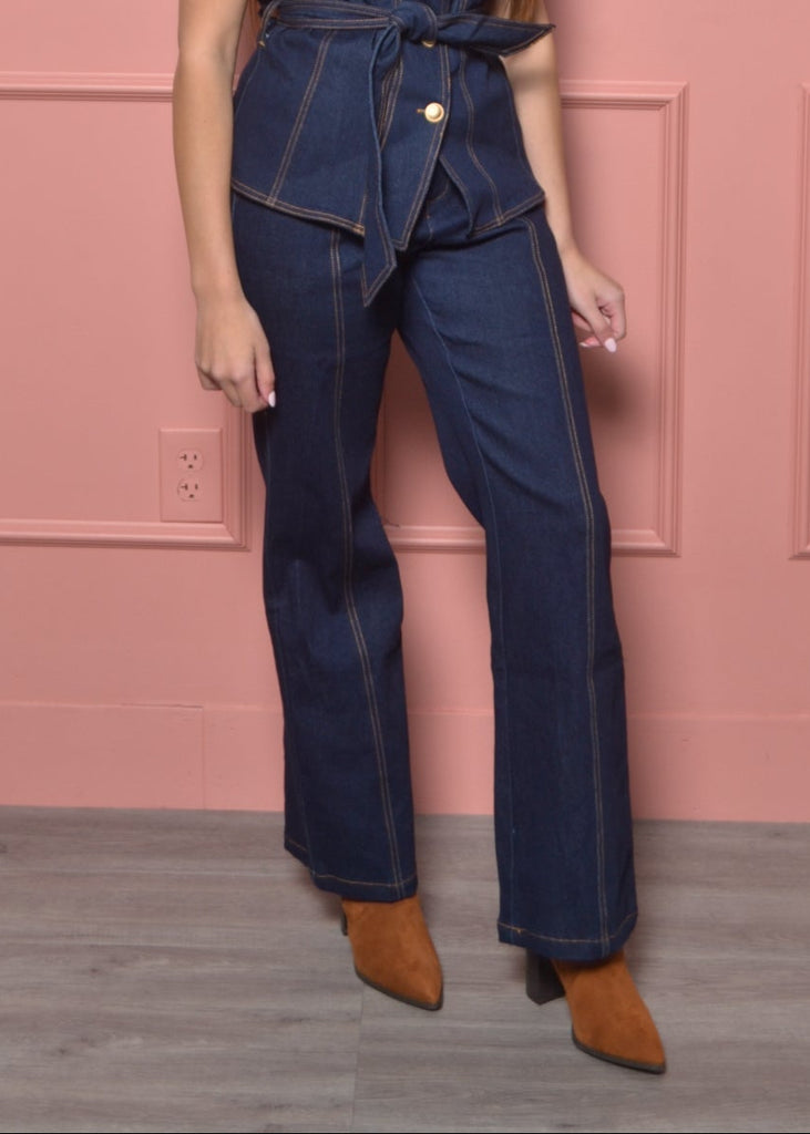 Woman wearing a denim outfit against a pink wall with wainscoting